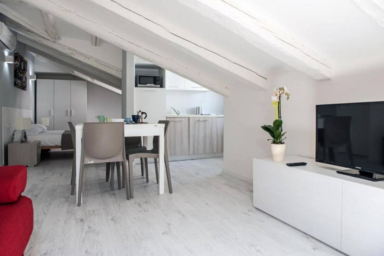 Bright attic studio with exposed beams, dining area, and kitchenette.